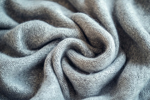 A close-up of a soft, gray knitted fabric showcasing intricate textures and fol, a Background Photo by ImageMir