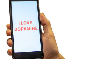 Hand holding smartphone with i love dopamine phrase, a Person Photo by DanFLCreativo