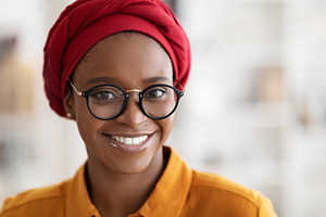 Closeup portrait of pretty young black lady wearing red headscarf, a Photo by Prostock-Studio