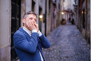Man plays harmonica outdoors in city