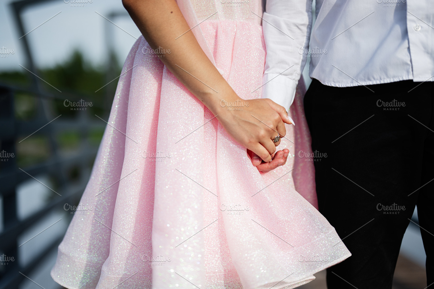Close-up of a couple holding hands wearing elegant attire outdoors, a Photo by AS photostudio