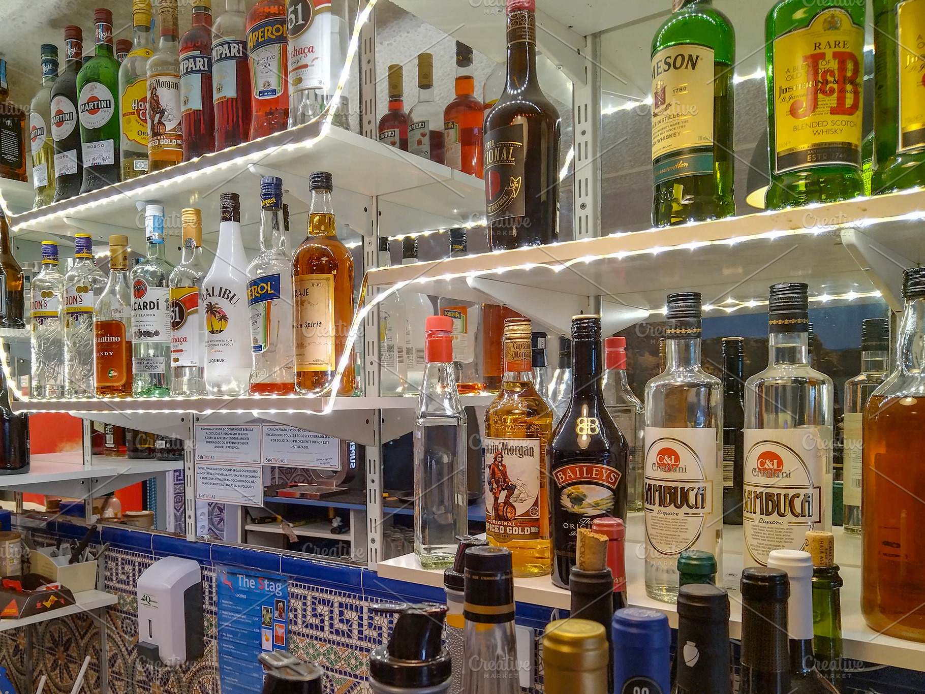 Shelves fully stocked with liquor bottles at a bar, a Food & Drink Photo by DanFLCreativo