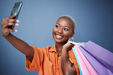 Selfie, happy and woman with shopping bags in studio after sale, promotion or discount. Smile, excited and African female person or customer taking picture after buying products by gray background., a Photo by Peopleimages.com
