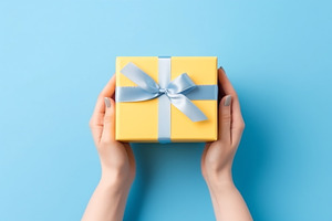 Gift wrapped in yellow held by hands, a Photo by Beautiful things