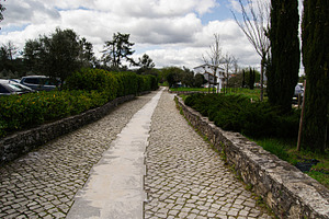Stone pathway surrounded by greenery in Fatima, Portugal on a cloudy day, a Photo by AS photostudio