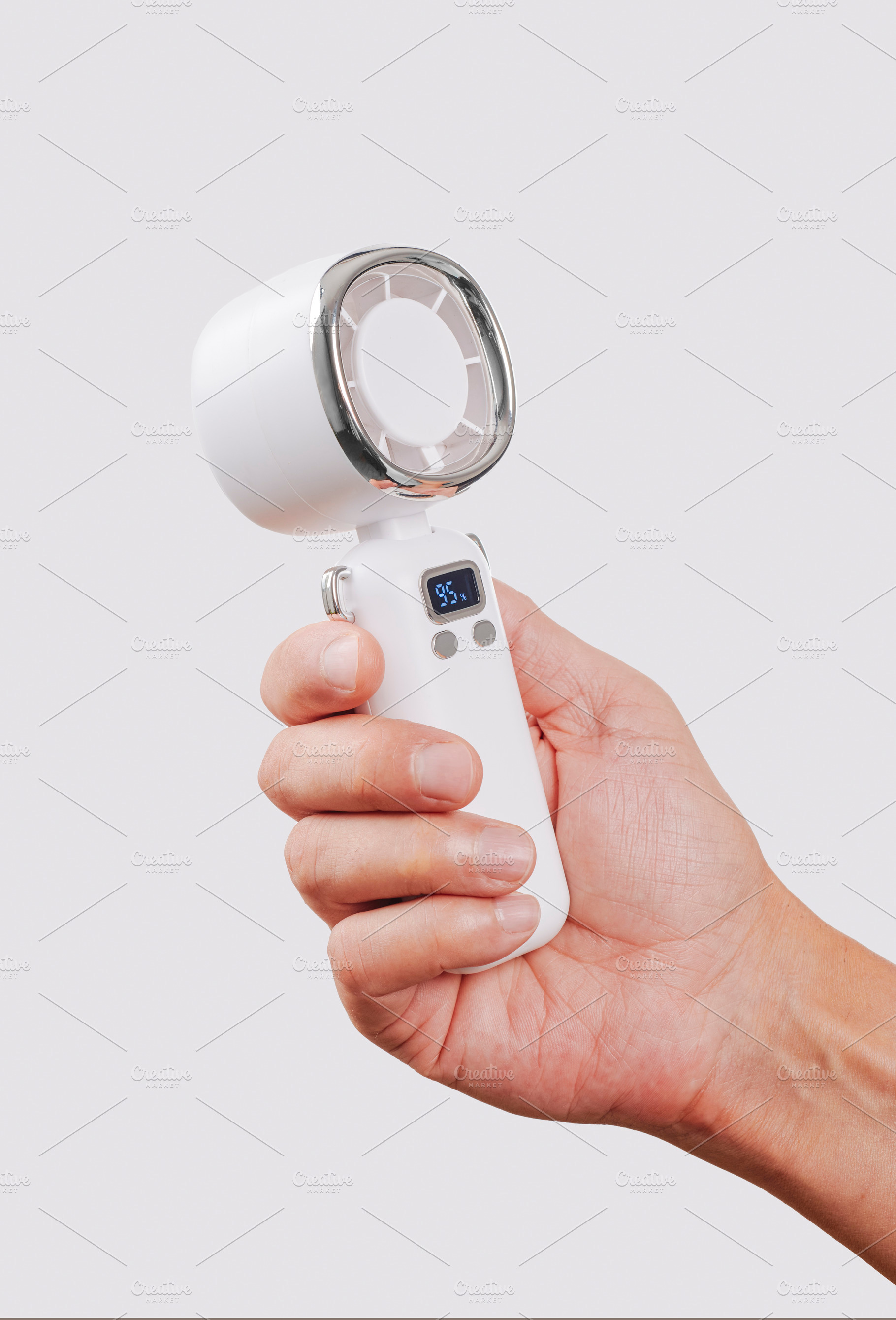 close-up of a man cooling himself with a white fan, a Photo by Nito