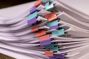 sheets of paper are connected by multicolored clips, stacked sheets of paper fo, a Photo by rsoollAI