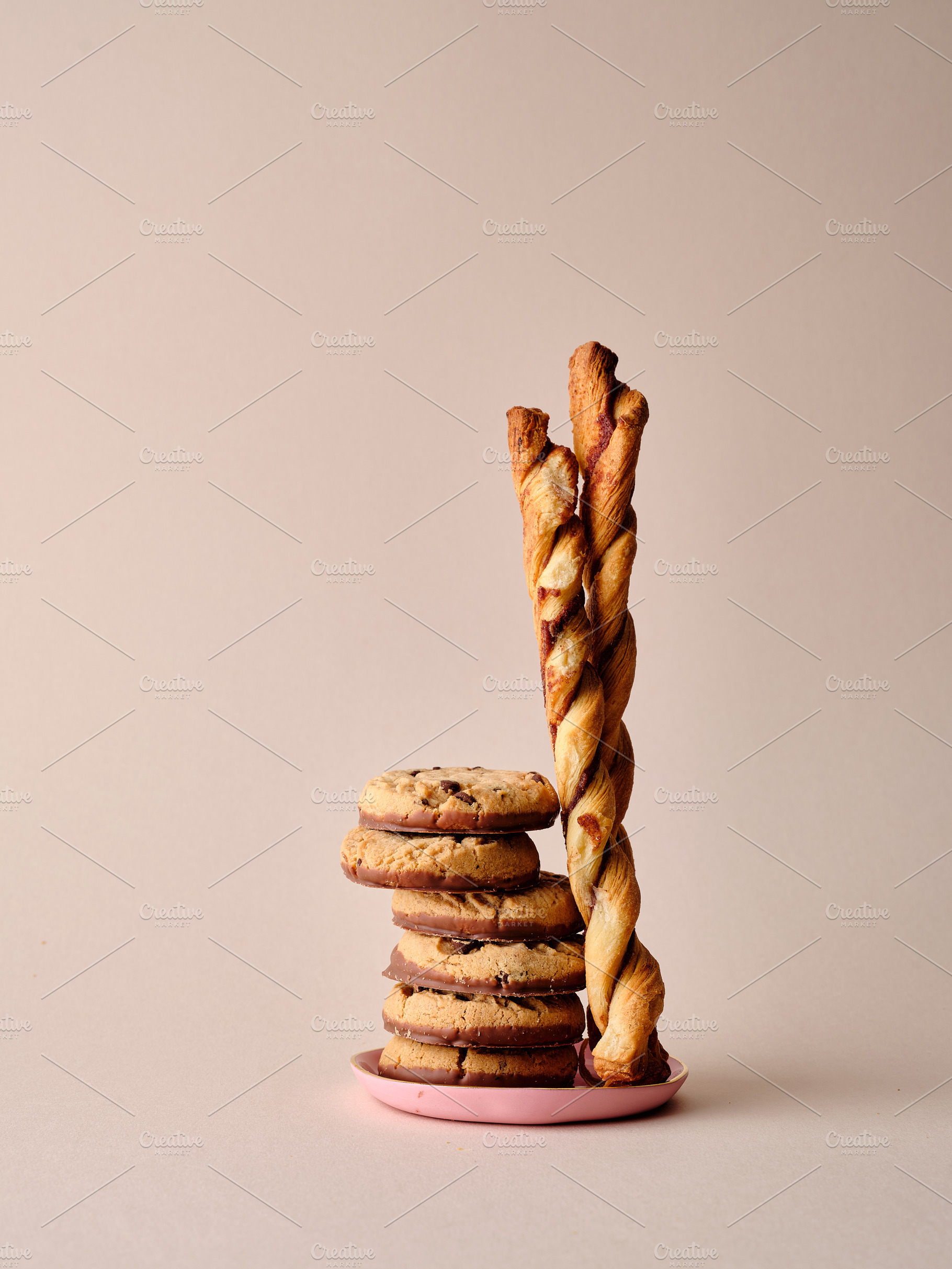 A stack of chocolate-covered biscuits and cookie sticks on beige, a Photo by Asya Nurullina