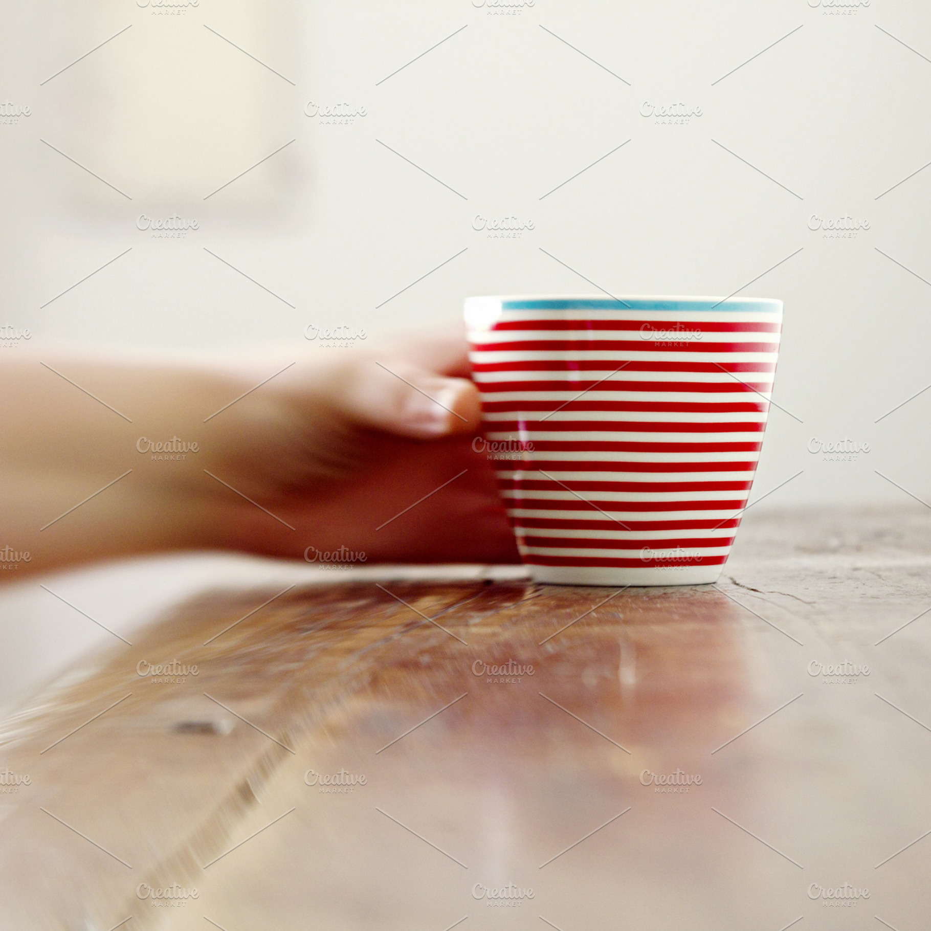 Blurry hand grabbing a striped mug, a Food & Drink Photo by Les Hirondelles Ph