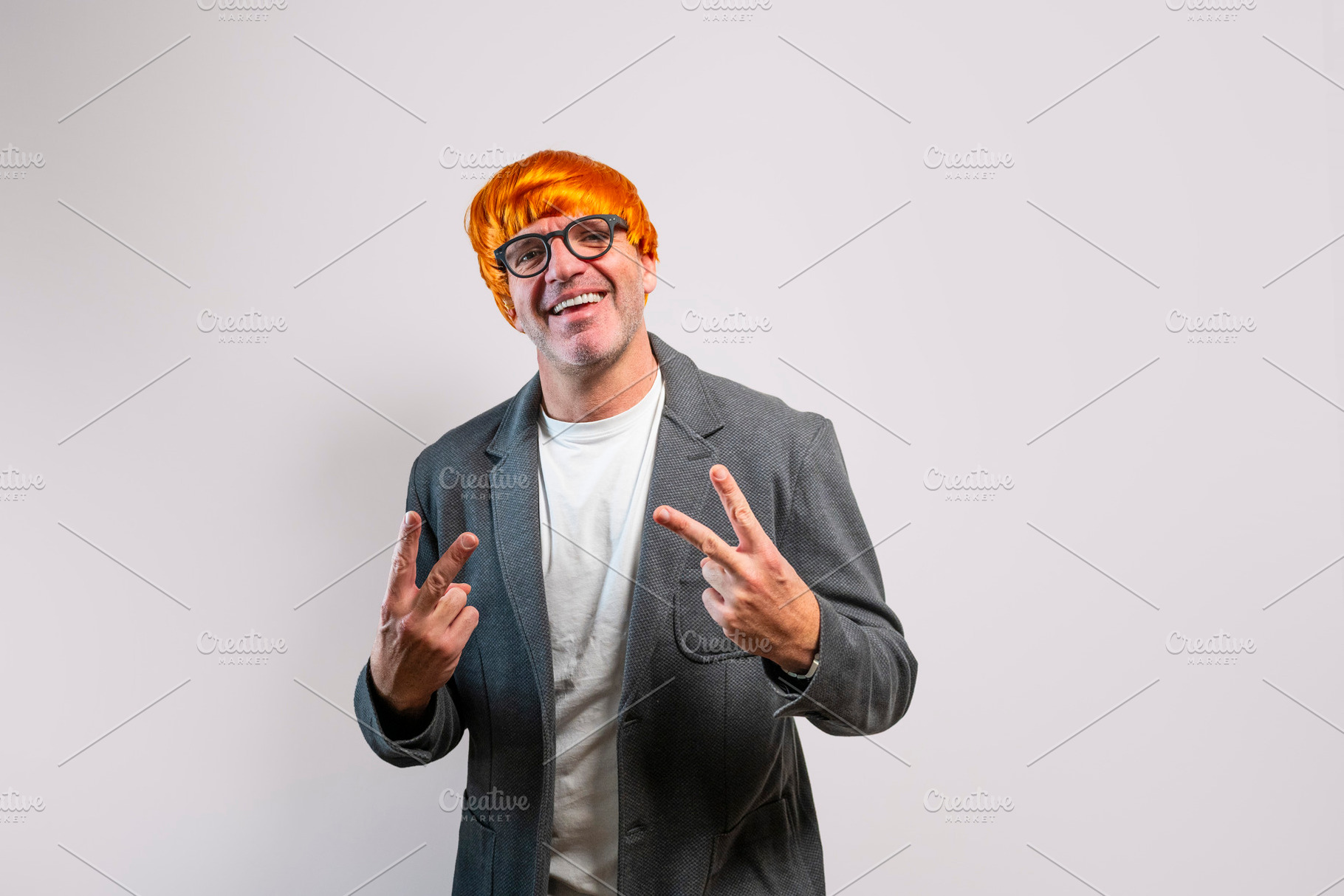 Man in orange wig making v sign smiling, a Person Photo by karrastock