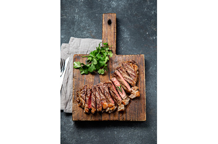 Fried strip loin steak on wooden, a Food & Drink Photo by LARISA BLINOVA