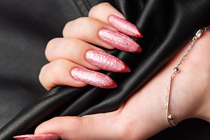 Woman hand with long acrylic pink nails holding leather, a Beauty & Fashion Photo by Olena Rudo