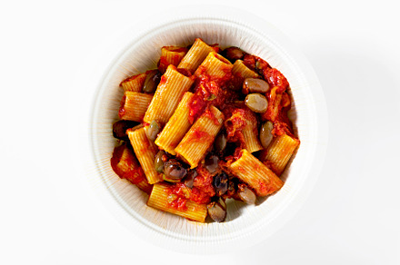 Italian tortiglioni pasta puttanesca with tomato sauce and black