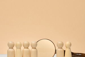 A row of wooden human figures stands on a light surface, and a m, a Business Photo by ndanko