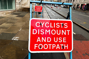 Cyclists dismount and use footpath red road sign directing pedes