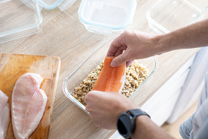 Man Preparing Salmon and Quinoa Meal in Food Container, a Food & Drink Photo by etorres69