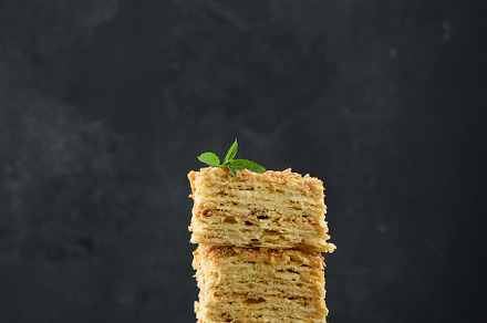 A stack of baked Napoleon pie slices with cream. Puff pastry, delicious dessert, a Food & Drink Photo by ndanko