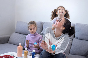 Mother with her two daughters happily painting Easter eggs at home, a Food & Drink Photo by etorres69