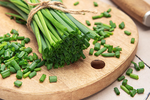 Freshly cut chives on wooden cutting board with knife, a Food & Drink Photo by Olena Rudo