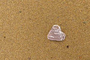 Single stone resting on sandy beach, a Background Photo by Elena Vagengeim