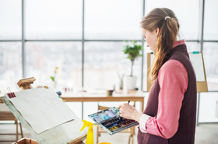 Portrait of a young woman painter drawing with watercolor palette on paper, an Arts & Entertainment Photo by undrey