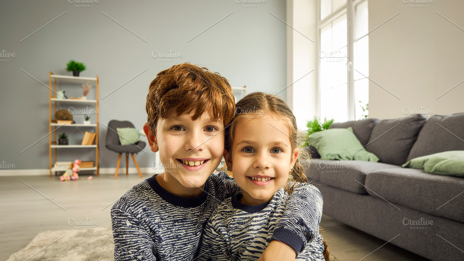 Two children smiling at camera on sofa, a Person Photo by DanFLCreativo