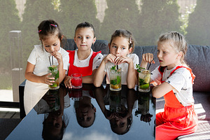 Group of children enjoying refreshing drinks at a cozy outdoor seating area, a Photo by AS photostudio