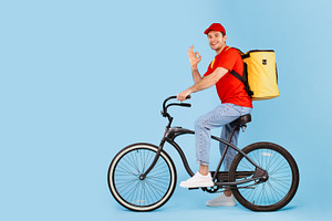 Deliveryman Riding Bike And Gesturing Okay On Blue Background, a Photo by Prostock-Studio