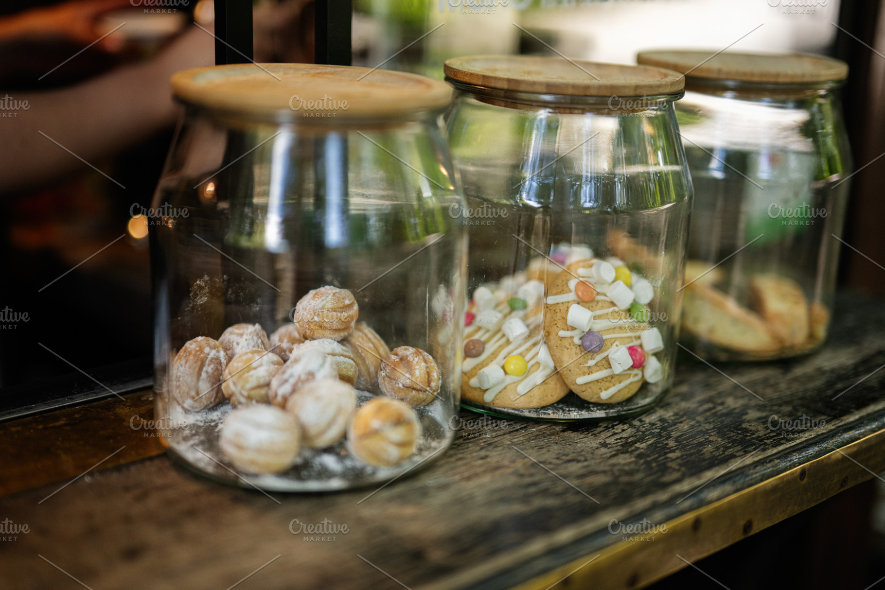 Glass jars filled with various delicious cookies on a wooden counter, a Photo by AS photostudio