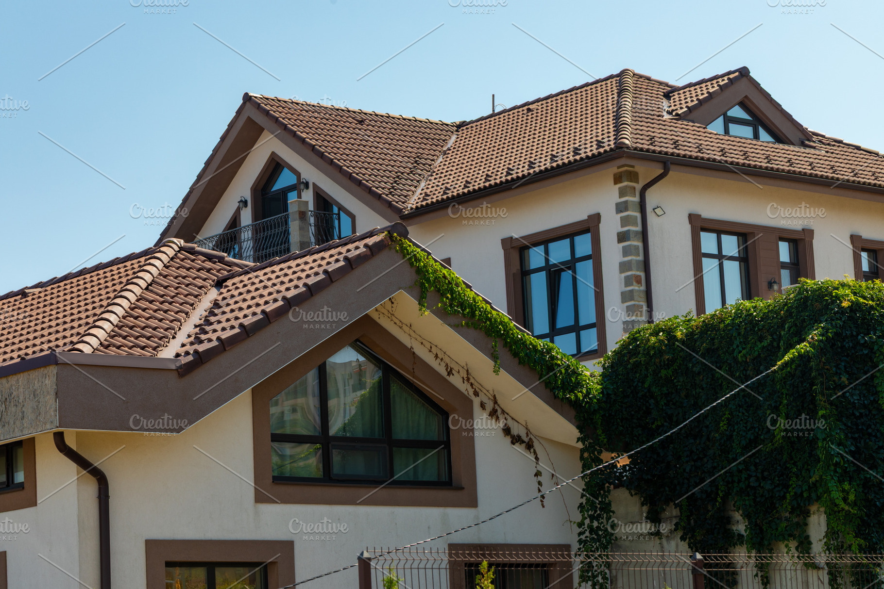 Contemporary house with brown tile roof, large windows, and lush green ivy clim, an Architecture Photo by Ales Munt