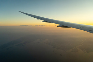 Airplane wing above Osaka coast during sunset descent flight, a Nature Photo by GoodGoods