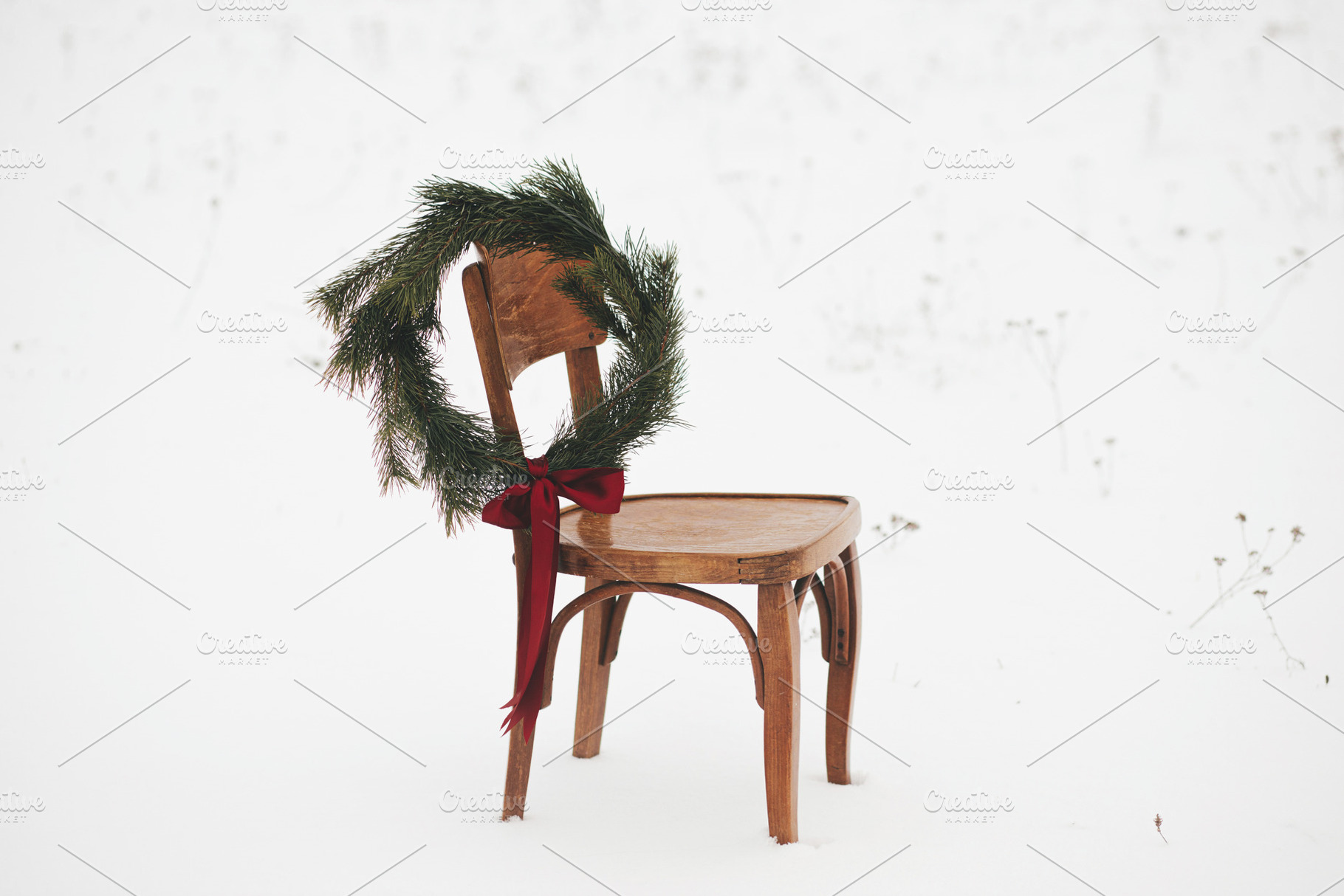 Christmas wreath on chair in snowy winter field. Merry Christmas, a Holiday Photo by Sonjachni