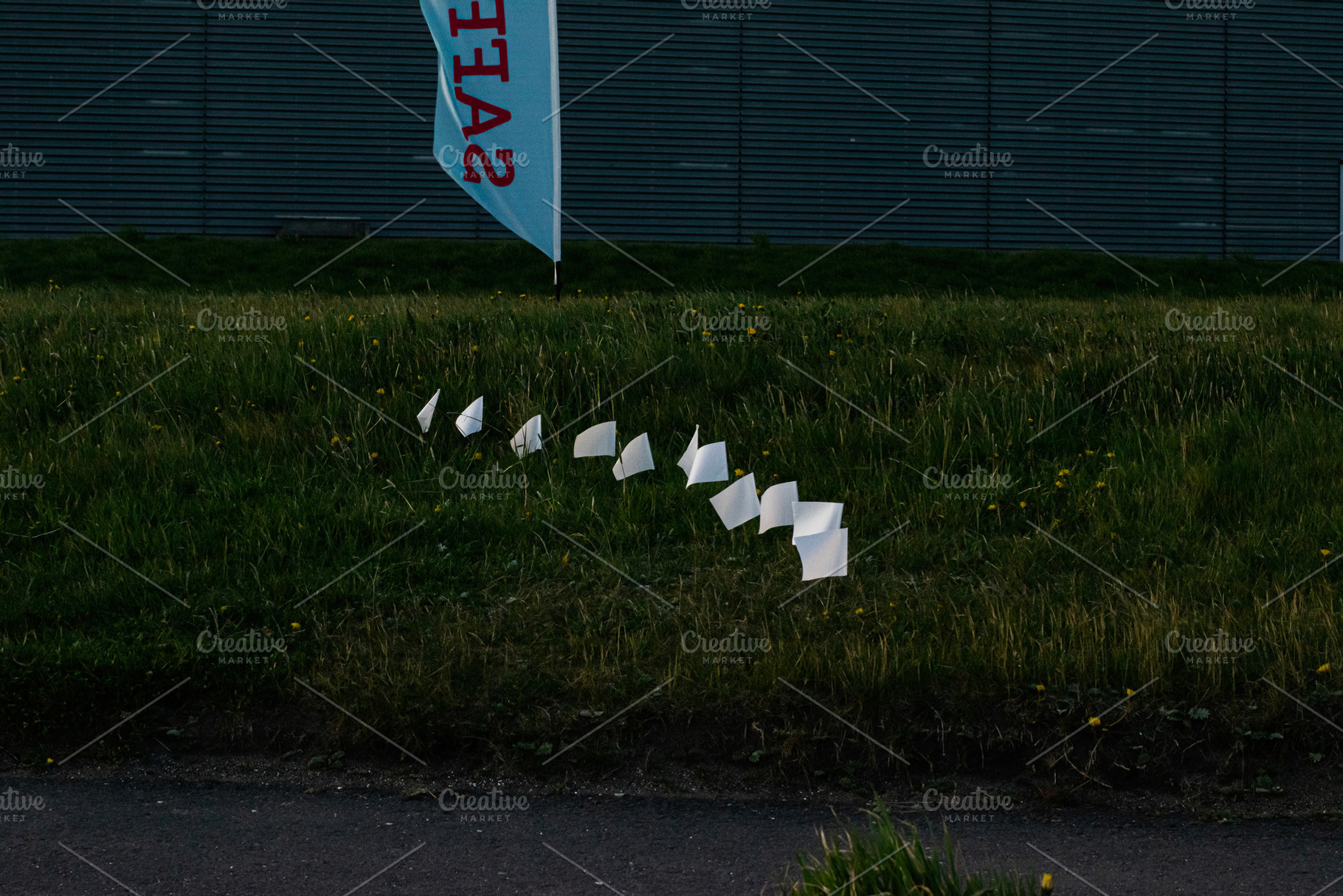 White flags placed on grass field near banner in Akranes, Iceland at evening, a Photo by AS photostudio