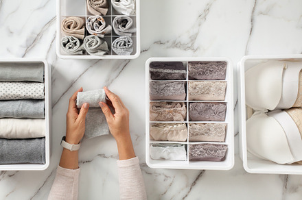 Woman hands placing organizer drawer divider with full of folded