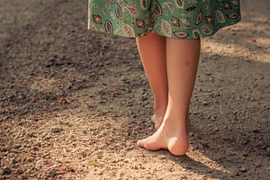 Young Girl Walks Barefoot on Road