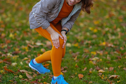 sad elegant woman in fitness clothes in park having leg pain, a Sports & Recreation Photo by Alliance Images