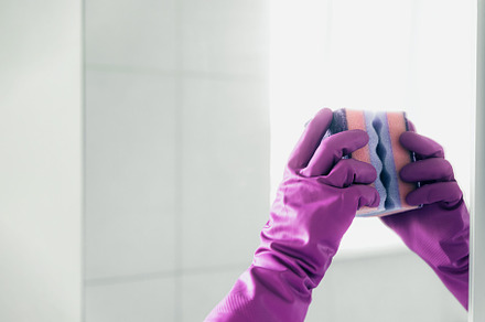 Housekeeper woman hand in rubber gloves polishing, cleaning mirror with pink ra, a Business Photo by Lenor4ik
