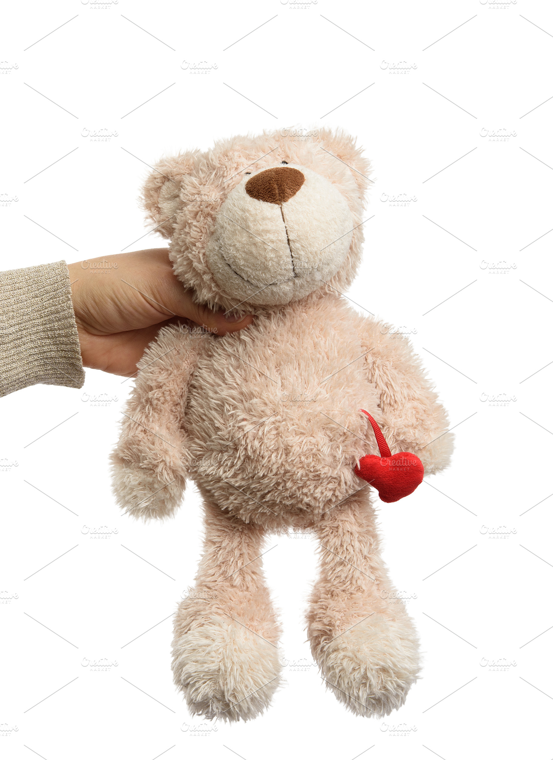 Human hand holding pink teddy bear with small red heart, isolate, an Abstract Photo by ndanko