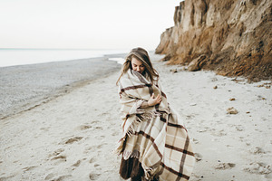 Woman walking along seashore with warm plaid artwork stock photo containing