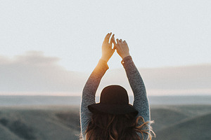Woman with arms raised at sunset