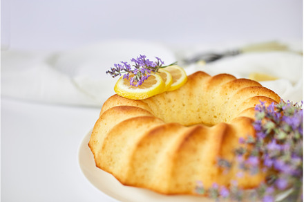 Round lemon cake on white table with, a Food & Drink Photo by IlliaBondarPhotography
