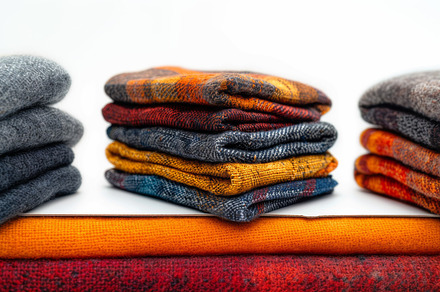 Stack of colorful wool clothing folded neatly on white background, a Photo by AS photostudio
