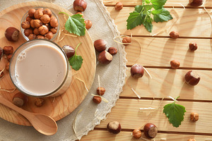 Glass of hazelnut drink on rustic table with hazelnut around, a Food & Drink Photo by Davizro's Market