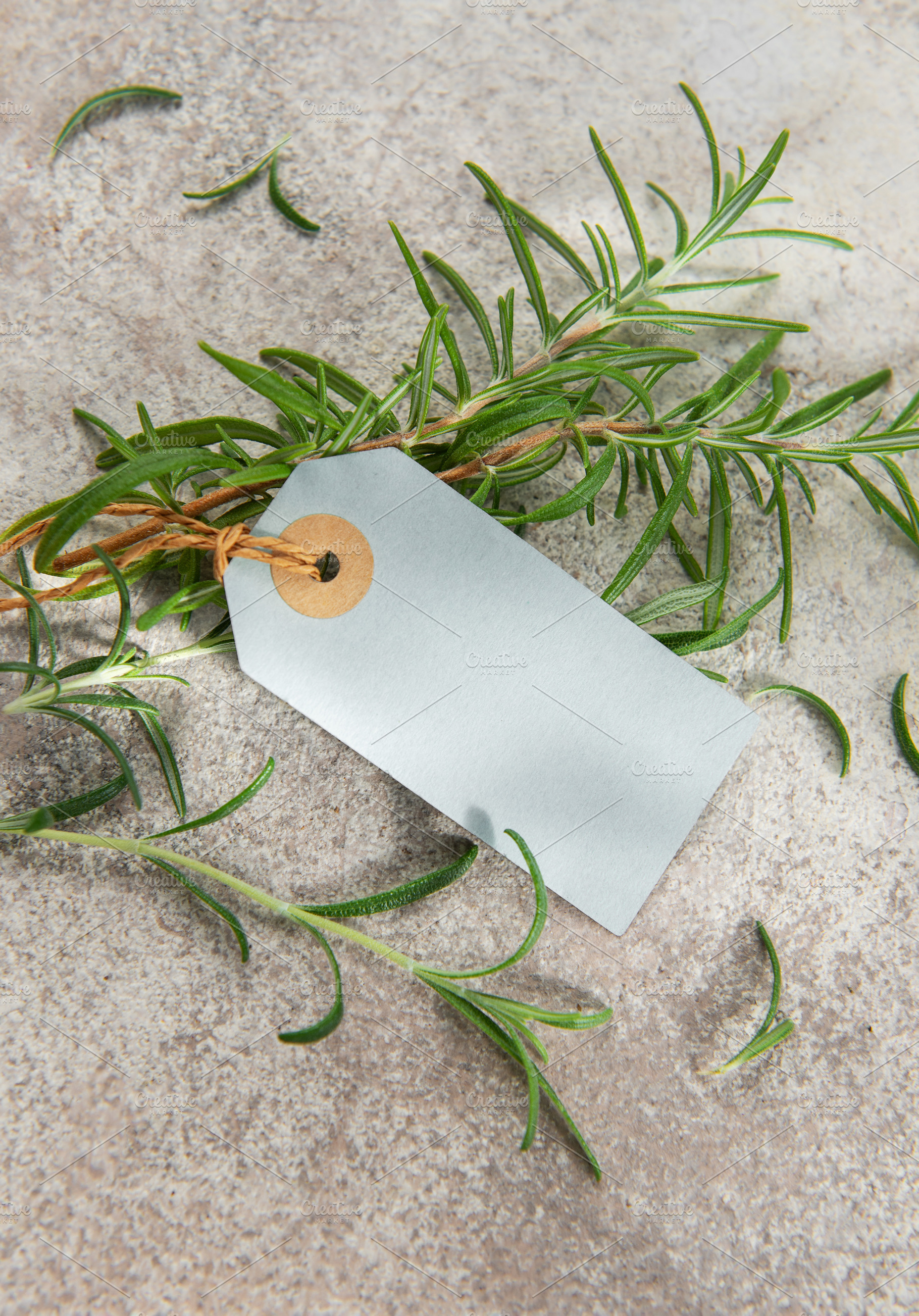 Fresh rosemary sprigs with blank tag on stone background, a Food & Drink Photo by Olena Rudo