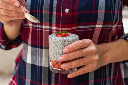 Female hands holding chia pudding with fresh strawberries for breakfast, a Food & Drink Photo by Antonina Vlasova