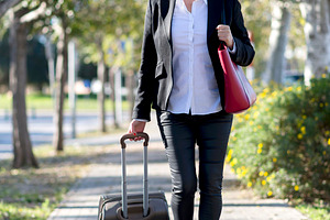Businesswoman walking with suitcase in city park, a Photo by RF Images