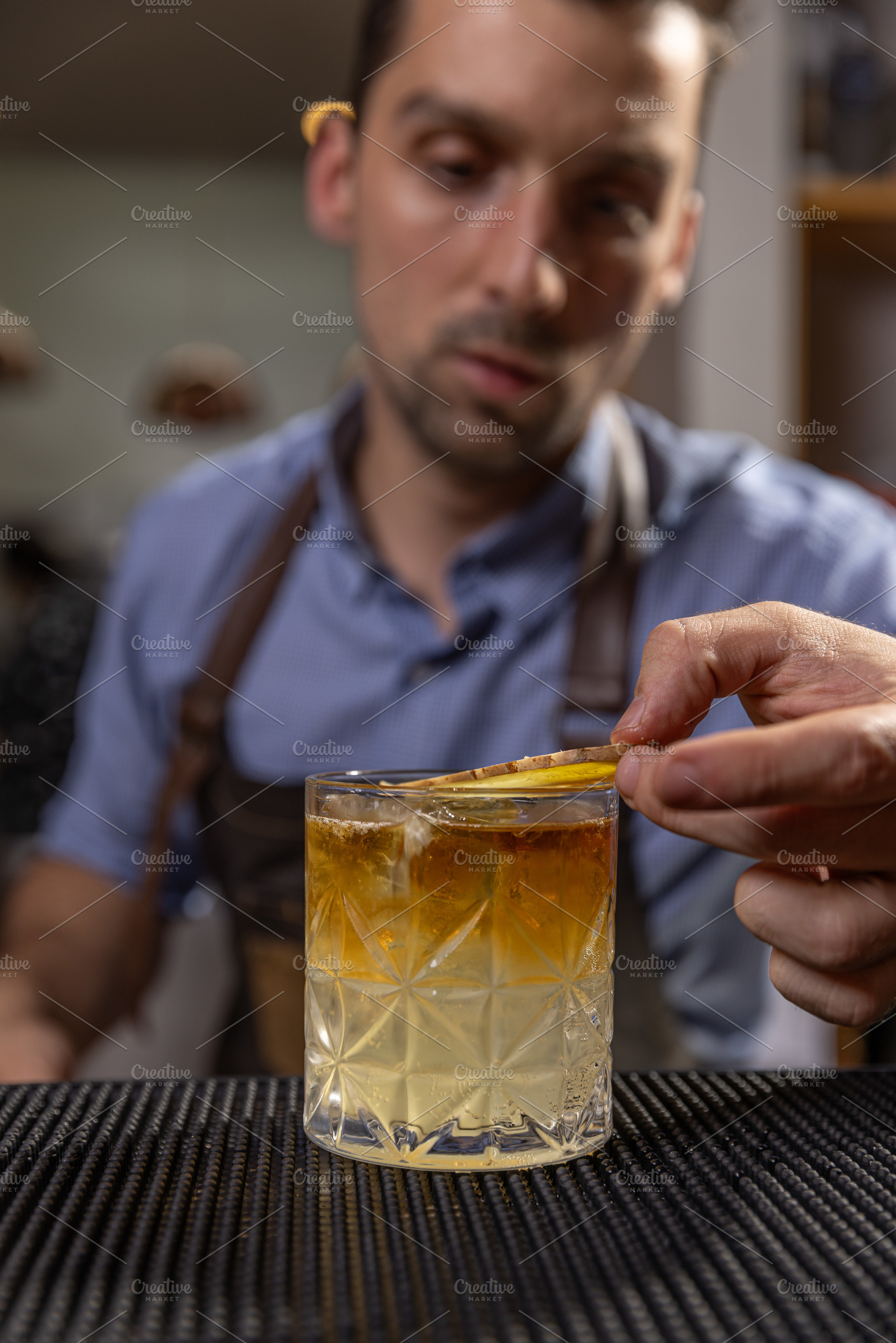 Bartender carefully garnishing a cocktail, a Photo by Grafvision photography
