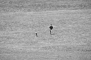 Man walking a dog in empty field, a Person Photo by BOOCYS