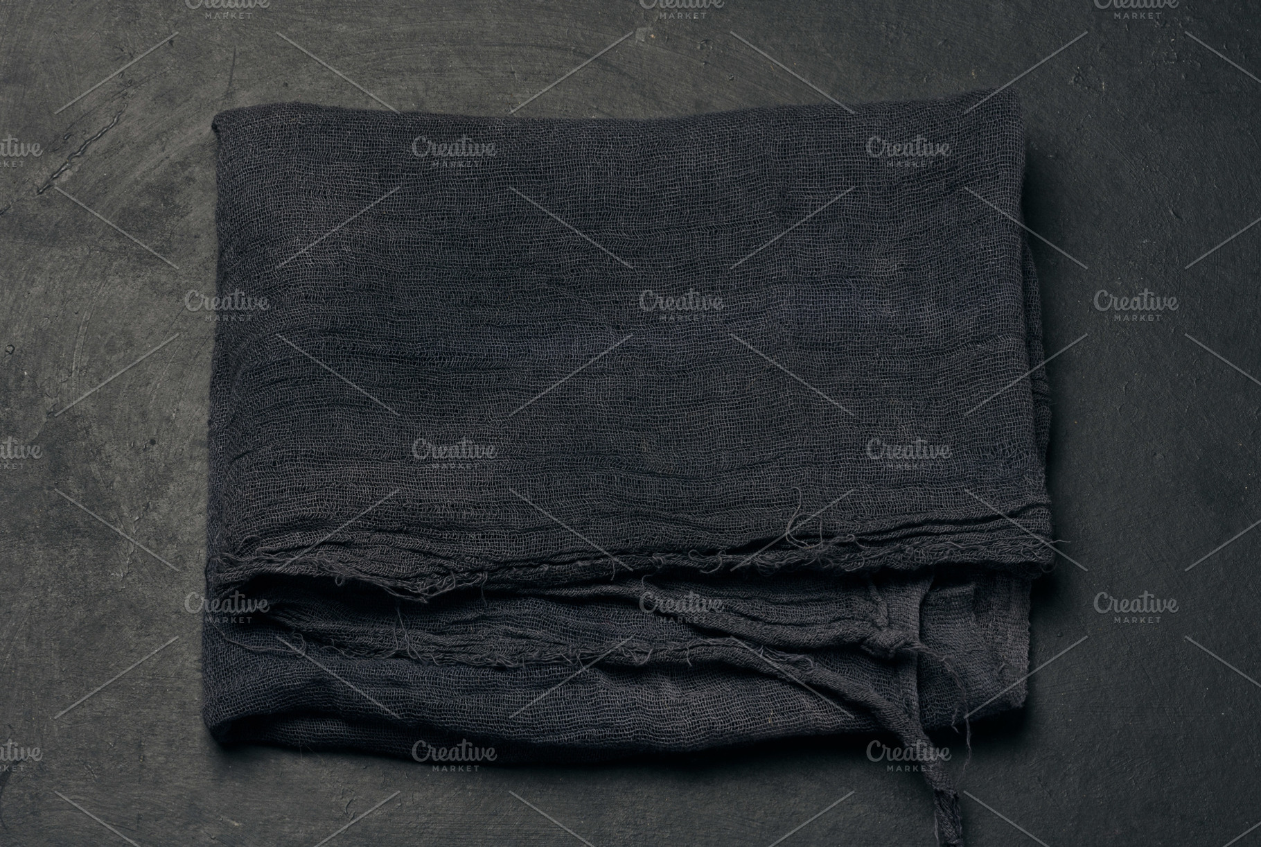 Folded black gauze kitchen napkin on black table, top view, a Food & Drink Photo by ndanko