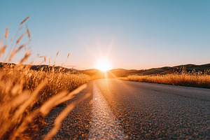 Scenic countryside road stretches before the sunset over rolling hills and gold, a Photo by AlyaAnd